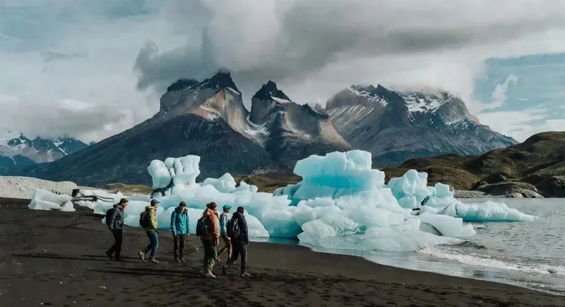 Small tour group at Grey Beach watching icebergs floating on the shoreline inside Torres del Paine National Park on a full-day tour departing from Punta Arenas, Chile