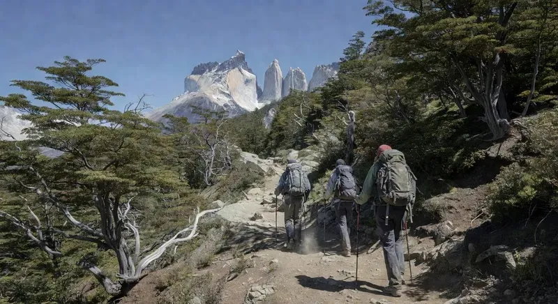 Hikers on the W Trek trail in Torres del Paine National Park with the three granite towers visible above the valley on a guided 5-day trekking tour in Chilean Patagonia